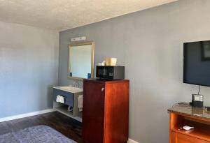 a room with a bathroom with a sink and a tv at Oasis Inn and Suites in Fallon