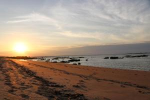 a beach with the sun setting over the water at Coconut Lodge in Kalumburu