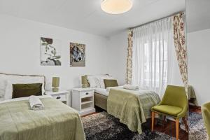 a bedroom with two beds and a chair and a window at Hambo Stay in Staffanstorp