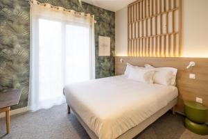 a bedroom with a white bed and a window at Le PIC in Clermont-Ferrand