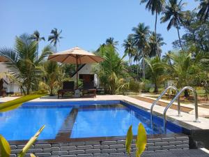 a pool at a resort with an umbrella at Green Luxe in Dambulla