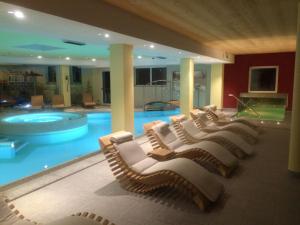 a row of chairs in front of a swimming pool at Nature Wellness Hotel Renato in Vigo di Fassa