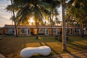 a white sculpture in front of a house with palm trees at TAM BoSa Beach Retreat in Kalyānpur