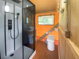 an orange bathroom with a shower and a toilet at Pheasant Lodge in Pangbourne