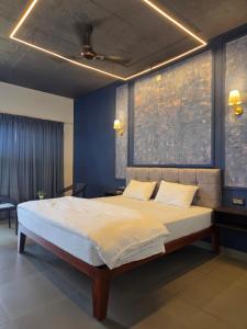 a bedroom with a large bed with blue walls at TAM BoSa Beach Retreat in Kalyānpur