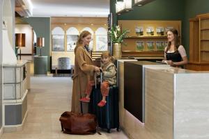 two women and a child sitting on a suitcase in a store at Arabella Alpenhotel am Spitzingsee, a Tribute Portfolio Hotel in Spitzingsee +148 photos