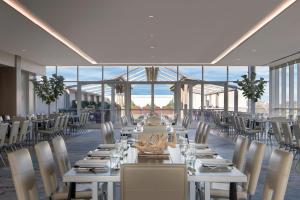 a dining room with white tables and chairs and windows at Renaissance Dallas Hotel in Dallas