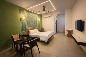 a bedroom with a bed and a table and a tv at TAM BoSa Beach Retreat in Kalyānpur +20 photos