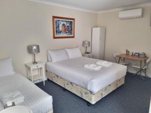 a bedroom with two beds and a table and a desk at Ongerup Hotel in Ongerup