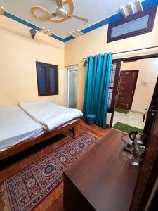 a bedroom with a bed and a table and blue curtains at Himalayan Stayz in Rishīkesh