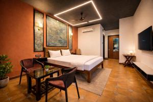 a hotel room with a bed and a table and chairs at TAM BoSa Beach Retreat in Kalyānpur