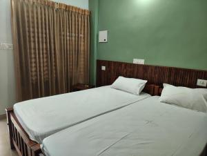 a bedroom with two beds with white sheets at Staysafe in Kattakkada +7 photos