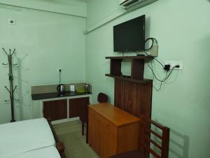 a bedroom with a bed and a tv on a wall at Staysafe in Kattakkada