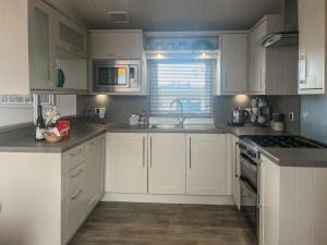 a kitchen with white cabinets and a stove top oven at Bluebell Lodge - Uk51382 in Wigton