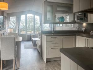 a kitchen with white cabinets and a dining room at Bluebell Lodge - Uk51382 in Wigton +8 photos