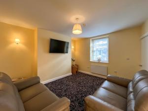 a living room with a couch and a flat screen tv at Albert Cottage in Llandudno