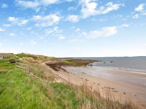 a beach with a bench next to the ocean at Wee Shore Walk in Balintore