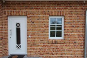 a brick wall with a white door and two windows at Borby-EG-Nr-2 in Haby
