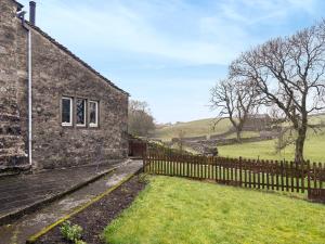 a stone house with a fence next to a field at Blindbeck Holiday Cottage in Settle