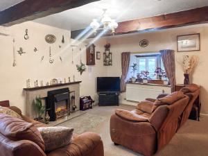 a living room with leather furniture and a fireplace at Blindbeck Holiday Cottage in Settle
