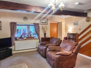 a living room with two chairs and a couch and a tv at Blindbeck Holiday Cottage in Settle