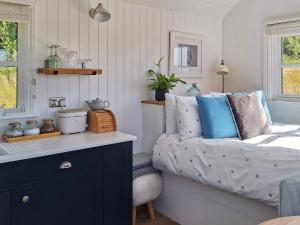 a bedroom with a bed with blue and white pillows at Pip's Hut in Bideford