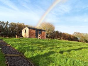 a house in a field with a rainbow in the sky at Pip's Hut in Bideford