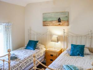 two beds in a bedroom with blue pillows at The Cottage in Broad Haven