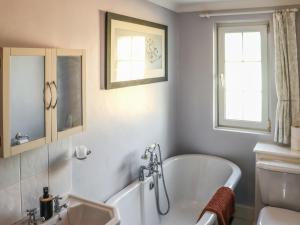 a bathroom with a tub and a sink at The Cottage in Broad Haven