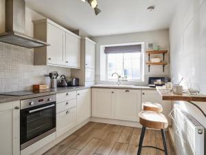 a kitchen with white cabinets and a sink at Hayy Bondgate Cottage in Harewood