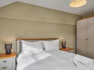 a bedroom with a large white bed with two lamps at Hayy Bondgate Cottage in Harewood