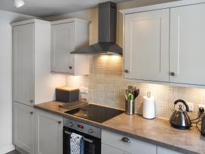 a kitchen with white cabinets and a sink at Hayy Bondgate Cottage in Harewood