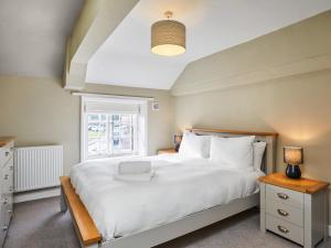 a bedroom with a white bed and a window at Hayy Bondgate Cottage in Harewood