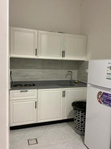 a kitchen with white cabinets and a white refrigerator at روڤان in Hafr Al-Batin