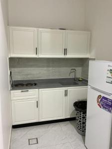 a kitchen with white cabinets and a sink and a refrigerator at روڤان in Hafr Al-Batin