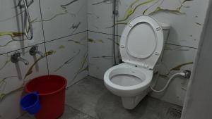 a bathroom with a toilet and a red bucket at Couples Nest in Kottakamboor