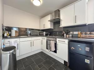 a kitchen with white cabinets and a black dishwasher at Sea View Apartment in Anstruther