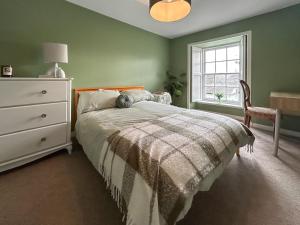 a bedroom with a bed and a dresser and a window at Sea View Apartment in Anstruther