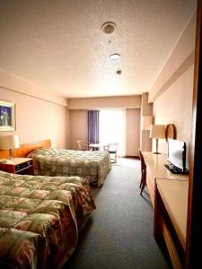 ein Hotelzimmer mit zwei Betten und einem Schreibtisch in der Unterkunft Hotel Kodama in Yamanouchi