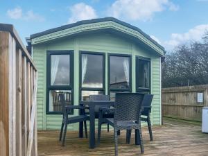 a green shed with a table and chairs on a deck at Oak Tree Lodge - Uk51429 in Westward