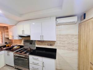 a kitchen with white cabinets and a stove top oven at Liberty Suite - Abuja in Abuja +5 photos