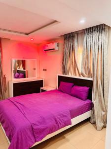 a bedroom with a purple bed and a window at Liberty Suite - Abuja in Abuja
