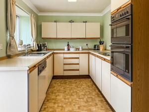 a kitchen with white cabinets and stainless steel appliances at Paddock Cottage in Morpeth