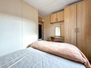 a bedroom with a bed and wooden cabinets at Wah Caravan in Dundee