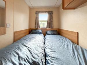 two beds in a small room with a window at Wah Caravan in Dundee