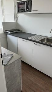 a white kitchen with a sink and a microwave at FeWo am Deich 4 in Bremerhaven