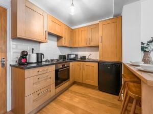 a kitchen with wooden cabinets and a black dishwasher at Old Steamship Quarters in Whitby
