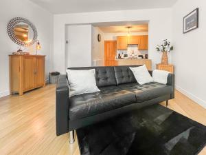 a black leather couch in a living room with a kitchen at Old Steamship Quarters in Whitby