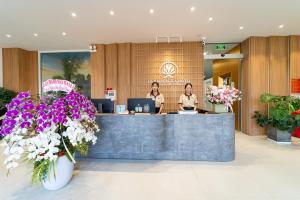 two women at a counter in a lobby with flowers at Quy Nhon Sea Hotel in Quy Nhon
