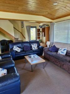 a living room with couches and a coffee table at Estuary Hideaway in Whangamata